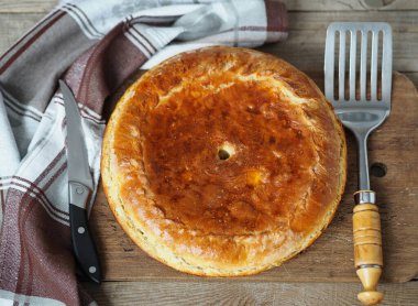 Eski bir ahşap arka planda peçeteyle doldurulmuş yuvarlak büyük turta. Şenlikli ya da sıradan ev yapımı pişirilmiş mallar..