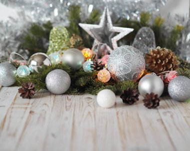 Noel toplarıyla dolu köknar dalları, beyaz ahşap bir masa üzerindeki yıldız ve süslemelerle dolu sakin bir hayat. Zarif gri arka plan. Ders için uygun..
