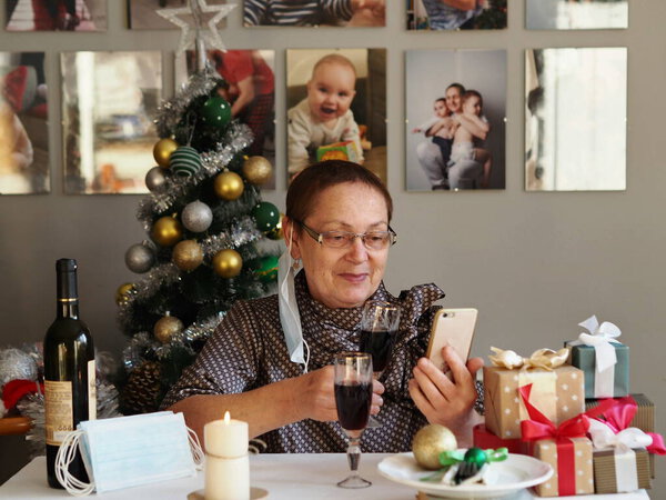 An elderly woman quarantined for coronavirus during Christmas eve alone meets the holiday and communicates with her family on the phone. The concept of coronavirus.