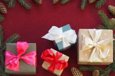 Noel hediyeleri köknar dallarıyla çevrili keçeli kırmızı bir zemin üzerine serilmiştir. Yeni Yıl ya da yeni yıl arkaplanını mesajlaşmak üzere kutlarız..