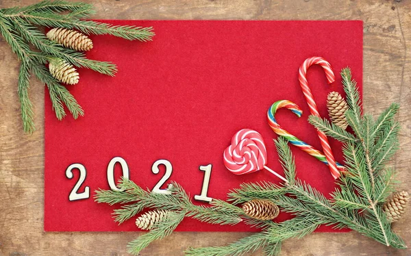祝贺卡片的背景 祝贺卡片的位置 编号2021的冷杉枝条和红色毛毡背景上的焦糖躺在一张木制桌子上 — 图库照片
