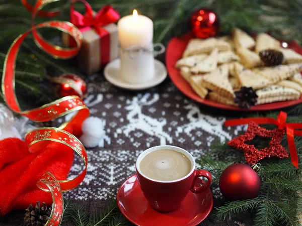 A cup of hot coffee with homemade shortbread cookies and red Christmas decor on a knitted knitted background with deer. Selective focus.Christmas background.Christmas background. — Stock Photo, Image