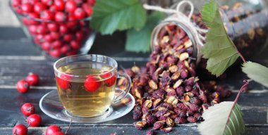 Kurumuş böğürtlen ve ahşap bir arka planda çay ile parlak taze yabanmersini. Dikeni kullanarak alternatif halk tıbbı..