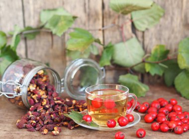 İleride kullanmak için kurumuş dikenleri topluyorum. Alternatif ilaç. Ahşap arka planda böğürtlenli bir fincan bitki çayı..