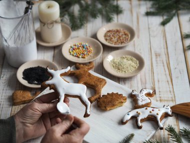 Yaşlı bir kadın Noel ya da yeni yıl tatiline hazırlanıyor ve ev yapımı kurabiyeleri hayvan şeklinde dekore ediyor..