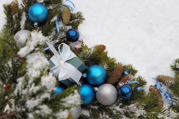 눈덮인 뒤쪽에 있는 가문비나무 가지에는 신년 (新年) 이라는 파란색, 노란색, 회색 공 모양의 돌기가 있고 선물 상자가 있다. 축하 문구가 적힌 크리스마스 카드. — 스톡 사진
