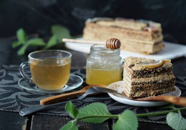 Koyu arkaplanda tereyağlı bal keki. Nane dalları, yeşil çay ve koyu arkaplanda bal. Gıda arkaplanı.