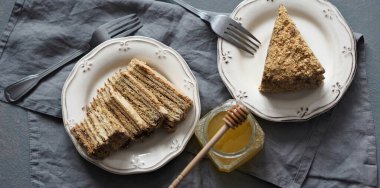 Gri bir arka planda ballı gri bir peçeteye iki parça ballı kek..