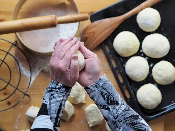 The process of cutting the dough into pieces for baking homemade buns.The woman\'s hands roll out the dough.A woman\'s hobby.Food background.