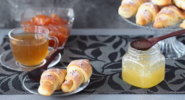 Koyu ahşap arka planda cam vazoda tereyağlı kruvasan. Çay için doğal bal ve reçel. Ders için uygun bir yer. Sağlıklı ev yemeği fikri..