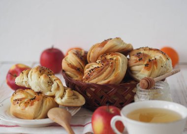 Beyaz tabakta bir fincan çay, bal ve meyve ile ev yapımı çörekler. Gıda arkaplanı.