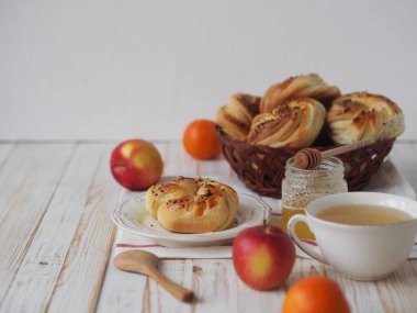 Beyaz tabakta bir fincan çay, bal ve meyve ile ev yapımı çörekler. Gıda arkaplanı.