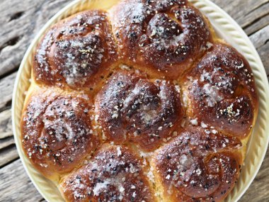 Yukarının manzarasını kapat. Ev yapımı çörekler reçel dolgulu, susam ve krema serpiştirilmiş eski bir ahşap arka planda.
