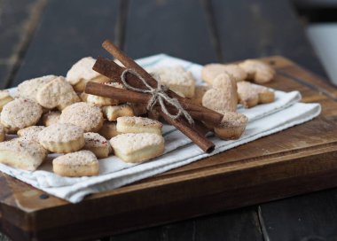 Tahta bir arka planda mutfak tahtasına tarçın çubukları serpiştirilmiş ev yapımı kurabiye serpiştirilmiş..