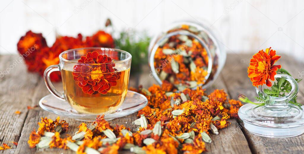 Useful properties of marigolds. The use of flowers Chernobrovtsy or Mary's Gold in folk alternative medicine. Fresh bright flowers of marigolds with dried flowers in a jar on a wooden background.