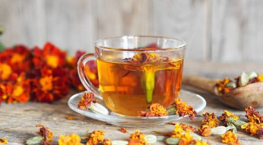 Kurumuş kırmızı çiçek çiçekleri siyah saçlı ya da altın sarısı Mary, ahşap arka planda bir fincan tıbbi çayla Türk karanfili. Bitki toplama mevsimi.