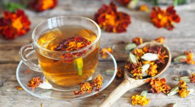 Sonbahar şifalı arka plan. Halk hekimliği. Kadife çiçekli bir bardak bitki çayı. Kurumuş çiçekli kadife çiçeği çayı sağlığına iyi gelir..