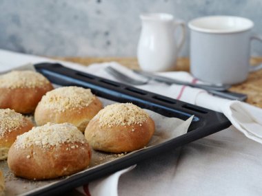 Fırından siyah bir kabartma çarşafının üzerinde tereyağlı hamburger ve bir bardak çay ya da kahve. Yemek hazır. Ev yemeği konsepti. Ekmek ve ekmekler.