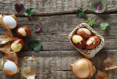Paskalya yumurtaları soğan kabuğuyla eski ahşap bir arka planda doğal bir sepetin içinde. Paskalya arkaplanı.