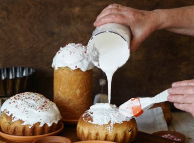 Ev yapımı Paskalya pastası yapma süreci. Bir kadın iyi pişmiş krema üzerine krem şanti sürer. Kahverengi arka plan kırsal tarzda.