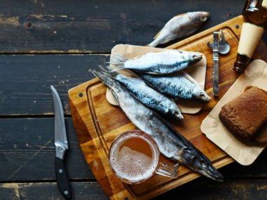 Bir bardak bira, bir dilim siyah ekmek ve kurutulmuş balık mutfak tahtasının üzerinde. Gıda arkaplanı.