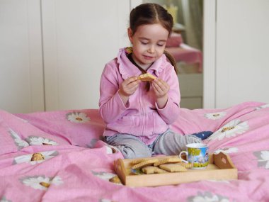 Yatağa otur, kurabiye ye ve süt iç. Gündüz vakti evde pembe elbiseli şirin bir kız var..