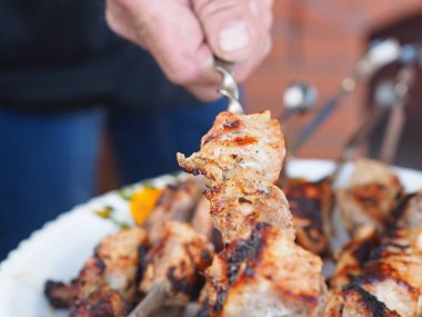 Bir adamın eli ev yapımı taze kebap ile bir şiş tutuyor. Doğal yiyecekler. Yemek fotoğrafı..