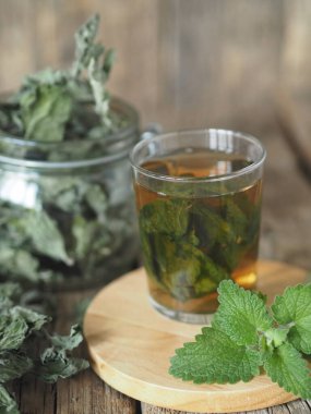 Kurutulmuş Melissa kullanarak şifalı bitki çayı. Melissa 'nın kurumuş yaprakları ya da eski ahşap bir masadaki bardakta taze bir dal ve tütsülenmiş nane şekeri..
