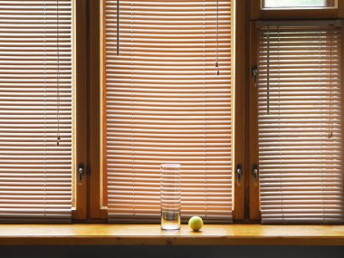 Şeffaf cam bir vazo ve ahşap pencere eşiğinde kapalı bir tenis topu. Minimalist konsept..