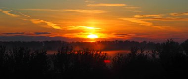 Ateşli güneşli şafak. Yaz sabahının başında. Sis sudan yükseliyor. Parlak renkli gündoğumu.