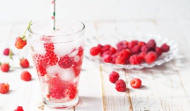 A glass of tonic with raspberries and ice. Quench your thirst in hot summer.