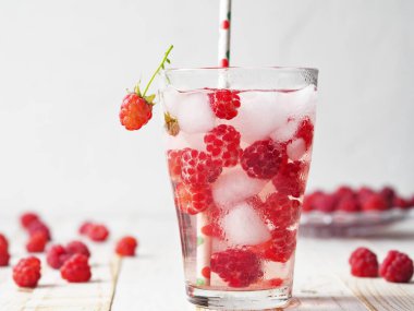 A glass of tonic with raspberries and ice. Quench your thirst in hot summer.
