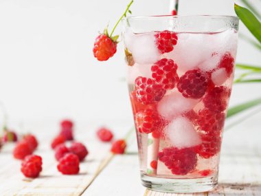 A glass of tonic with raspberries and ice. Quench your thirst in hot summer.