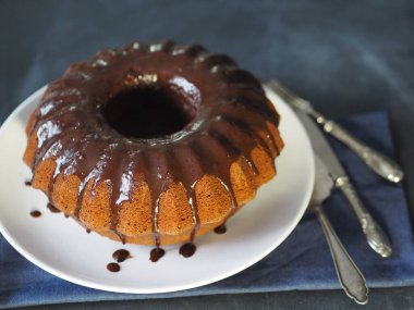 Çikolatalı, yuvarlak kek, ahşap bir arka planda, mavi bir peçeteyle. Koyu arkaplan.