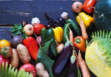Kırsalda yetişen çeşitli doğal sebzeler ve meyveler, koyu ahşap bir arka planda. Sonbahar hasadı. Boş kopyalama alanı.