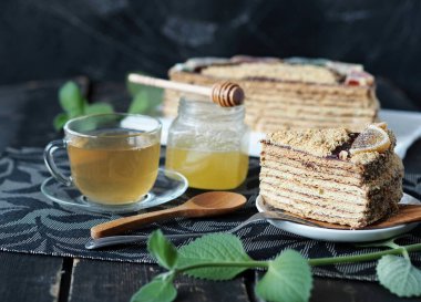 Koyu arkaplanda tereyağlı bal keki. Nane dalları, yeşil çay ve koyu arkaplanda bal. Gıda arkaplanı.