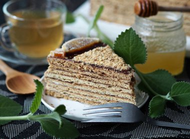 Koyu arkaplan üzerine katmanlı ballı kek. Nane dalları, yeşil çay ve koyu arkaplanda bal. Gıda arkaplanı.