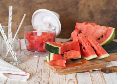 Mutfaktaki masada bir bardak taze karpuz suyu. Olgun karpuzlar ve arka planda dilimler. Vitamin açısından zengin sağlıklı eko tatlı yiyecekler. Organik tarımın popüler ürünü.