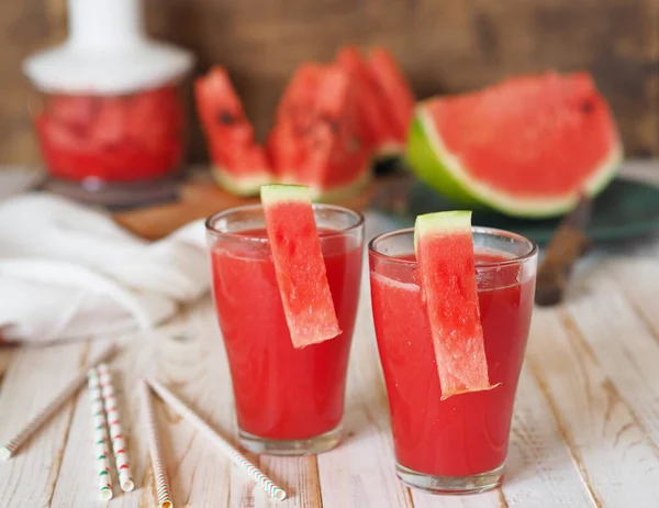 Gelas jus segar, semangka smoothie di atas meja di kitchen.Ripe semangka dan irisan di latar belakang. Makanan alami yang sehat. Semangka adalah produk makanan organik yang populer. — Stok Foto
