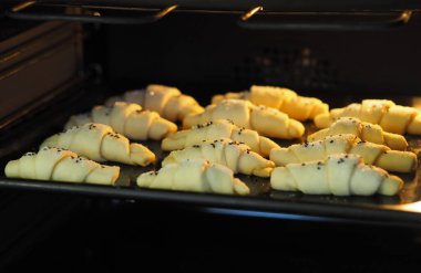 Kadın eli mutfak fırınından yeni pişmiş kruvasan tutuyor. Gıda arkaplanı.