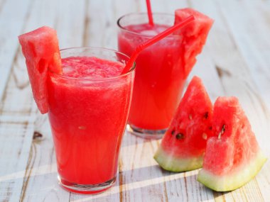 Doğal sağlıklı ürün. Tahta beyaz bir masada buzlu kırmızı karpuz posasından soğuk bir içecek..