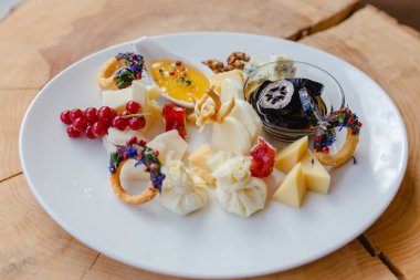 Restoranda peynir servis edip servis etmek. Peynirli peynir tabağı, bal, şuruplu fındık, böğürtlen ve doğal ahşap arka planda otlar..