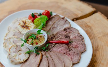 Restoranda et tabağı var. Haşlanmış dil dilimleri, tavuk rulosu ve domuz eti fırında sarımsak, vişneli domates, kırmızı biber ve ağaç kesiminde bezelye filizi ile hardal dilimleri..
