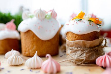 Ortodoks Paskalya 2021. Pasta dekorasyonu. Beyaz kremalı kekler, pembe ve beyaz kremayla süslenmiş, çiçekler ve doğal ahşap arka planda bitkiler. Paskalya kartı.