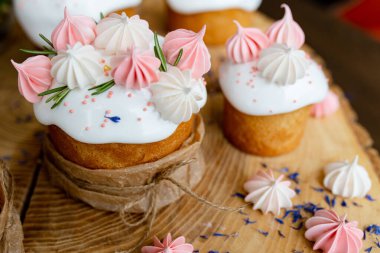 Ortodoks Paskalya 2021. Pasta dekorasyonu. Beyaz kremalı kekler, pembe ve beyaz kremayla süslenmiş, çiçekler ve doğal ahşap arka planda bitkiler. Paskalya kartı.