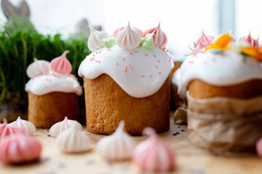 Ortodoks Paskalya 2021. Pasta dekorasyonu. Beyaz kremalı kekler, pembe ve beyaz kremayla süslenmiş, çiçekler ve doğal ahşap arka planda bitkiler. Paskalya kartı.