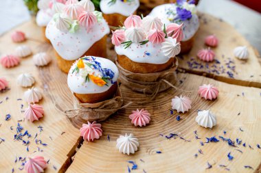 Ortodoks Paskalya 2021. Pasta dekorasyonu. Beyaz kremalı kekler, pembe ve beyaz kremayla süslenmiş, çiçekler ve doğal ahşap arka planda bitkiler. Paskalya kartı.