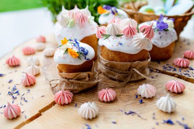 Ortodoks Paskalya 2021. Pasta dekorasyonu. Beyaz kremalı kekler, pembe ve beyaz kremayla süslenmiş, çiçekler ve doğal ahşap arka planda bitkiler. Paskalya kartı.