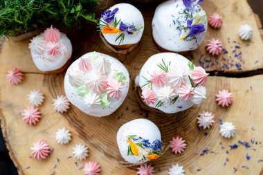 Ortodoks Paskalya 2021. Pasta dekorasyonu. Beyaz kremalı kekler, pembe ve beyaz kremayla süslenmiş, çiçekler ve doğal ahşap arka planda bitkiler. Paskalya kartı.