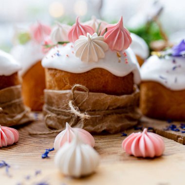 Ortodoks Paskalya 2021. Pasta dekorasyonu. Beyaz kremalı kekler, pembe ve beyaz kremayla süslenmiş, çiçekler ve doğal ahşap arka planda bitkiler. Paskalya kartı.